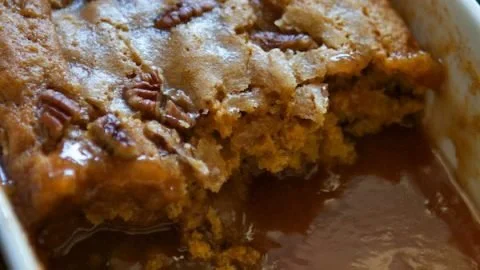 A delicious pumpkin pecan cobbler served in a rustic dish, topped with whipped cream.